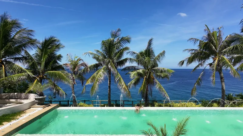 Palm trees above a turquoise pool with the ocean beyond